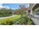 Lush green front yard featuring flowering trees, decorative shrubbery, and a stone walkway toward the porch at 6050 Saddle Oak Trl, Sarasota, FL 34241