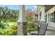 Cozy porch with stone columns, comfortable seating, and views of the manicured yard and driveway at 6050 Saddle Oak Trl, Sarasota, FL 34241