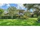 Stately home featuring manicured lawn, lush landscaping, and a grand entrance with large windows and decorative trees at 6905 Pine Valley St, Bradenton, FL 34202