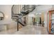 Elegant foyer with a striking spiral staircase, marble floors, and a view into the light-filled living room beyond at 6905 Pine Valley St, Bradenton, FL 34202