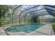 A screened-in pool area with blue water surrounded by lush greenery, providing a serene and private outdoor retreat at 6905 Pine Valley St, Bradenton, FL 34202