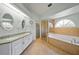 Bathroom featuring double sinks, a glass-enclosed shower, and a soaking tub under an arch window at 7115 39Th E Ln, Sarasota, FL 34243