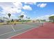 Outdoor tennis court with players, showcasing community amenities under a sunny sky with palm trees at 7115 39Th E Ln, Sarasota, FL 34243