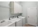 Well-equipped laundry room with washer, dryer, sink, and storage cabinets at 7130 Westhill Ct, Lakewood Ranch, FL 34202