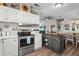 Kitchen with stainless steel appliances, white cabinetry, a center island and is open to the dining and living areas at 8470 Imperial Cir, Palmetto, FL 34221