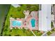Overhead view of two blue pools, a hot tub, lounge area, tiki hut and landscaping at 8470 Imperial Cir, Palmetto, FL 34221