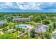 Aerial view of the community pool and lounge area with nearby buildings and palm trees in a tropical landscape at 8827 Manor Loop # 208, Lakewood Ranch, FL 34202