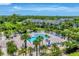 Beautiful aerial view of a community pool with lounge chairs and palm trees, surrounded by townhomes and lush trees at 8827 Manor Loop # 208, Lakewood Ranch, FL 34202