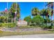 Welcome to 'The Village at Town Park' displayed on a beautifully landscaped sign surrounded by palm trees and American flags at 8827 Manor Loop # 208, Lakewood Ranch, FL 34202
