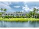 Picturesque waterfront view of well-maintained townhouses with lush landscaping and palm trees reflecting in the calm water at 8827 Manor Loop # 208, Lakewood Ranch, FL 34202