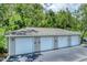 This shows a row of four garages with white doors and beige siding, topped with a gray roof and surrounded by green trees at 8827 Manor Loop # 208, Lakewood Ranch, FL 34202