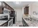 Close-up of kitchen features stainless steel appliances, granite counters, and dark wood cabinetry at 8827 Manor Loop # 208, Lakewood Ranch, FL 34202