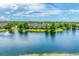 Scenic aerial view of a community pond and fountain surrounded by lush trees and townhouses under a partly cloudy sky at 8827 Manor Loop # 208, Lakewood Ranch, FL 34202