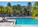 Exterior view of a community pool, surrounded by lush greenery, set against the backdrop of the clubhouse and palm trees at 8827 Manor Loop # 208, Lakewood Ranch, FL 34202