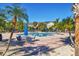 Community swimming pool with lounging chairs and nearby townhouses under a sunny sky, surrounded by lush palm trees at 8827 Manor Loop # 208, Lakewood Ranch, FL 34202