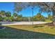 The sand volleyball court with a light, set amidst manicured green grass and tropical palms on a clear day at 8827 Manor Loop # 208, Lakewood Ranch, FL 34202