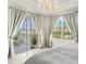 Bright main bedroom offers a chandelier, and sliding glass doors to balcony at 1000 San Lino Cir # 1032, Venice, FL 34292