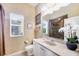 Bathroom with neutral patterned wallpaper, a large mirror, and a sink with white cabinets at 1017 Tuscany Blvd, Venice, FL 34292