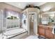 Main bathroom features a soaking tub, sink with wood cabinets, and a walk-in shower at 1017 Tuscany Blvd, Venice, FL 34292