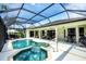 Exterior view of a covered, screened-in pool and spa area featuring lounge chairs and covered dining at 1017 Tuscany Blvd, Venice, FL 34292