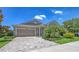 Inviting home showcasing a two-car garage, brick driveway, neat landscaping, and a blend of trees and flowering plants at 11223 Spring Gate Trl, Bradenton, FL 34211