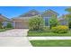 Single-Gathering home with a tan exterior, a two-car garage, brick driveway, and manicured landscaping under a blue sky at 11223 Spring Gate Trl, Bradenton, FL 34211