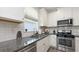 Well-lit kitchen featuring granite counters, stainless steel appliances, white cabinets and drawers, with tile flooring at 11223 Spring Gate Trl, Bradenton, FL 34211