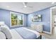 Bright bedroom with blue walls, a ceiling fan, and a large window showcasing lush greenery at 119 Avenida Messina, Sarasota, FL 34242