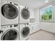 Laundry room with full-size washer and dryer, white cabinetry, and natural light from the exterior window at 119 Avenida Messina, Sarasota, FL 34242