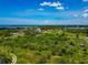 Overhead view of a lush, green neighborhood, featuring scattered homes with a clear waterfront in the distance at 1230 Bayshore Dr, Terra Ceia, FL 34250