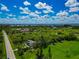 Aerial view of a property with a lush landscape, adjacent roadways, and distant water views under a partly cloudy blue sky at 1230 Bayshore Dr, Terra Ceia, FL 34250
