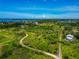 Lush aerial view of a sprawling green space featuring dirt road access, waterfront views, and scattered homes with a vibrant blue sky at 1230 Bayshore Dr, Terra Ceia, FL 34250