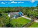 Aerial shot of home with small yard, mature landscaping, damage to roof covered by tarp, and fenced yard at 1230 Bayshore Dr, Terra Ceia, FL 34250