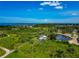 Aerial view of property with a charming pond, green fields, and a home set against a backdrop of water and blue skies at 1230 Bayshore Dr, Terra Ceia, FL 34250