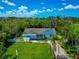 Single-story home with a damaged roof, surrounded by green grass and lush trees in a serene neighborhood at 1230 Bayshore Dr, Terra Ceia, FL 34250
