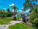 Home featuring a small yard, mature landscaping, fenced yard, gate, and damage to roof covered by tarp at 1230 Bayshore Dr, Terra Ceia, FL 34250