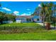 Exterior of home featuring a small yard, mature landscaping, and damage to roof covered by tarp at 1230 Bayshore Dr, Terra Ceia, FL 34250