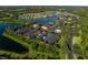 Aerial view showcasing the townhome community with a scenic lake, lush greenery, and ample parking at 13084 Tigers Eye Dr, Venice, FL 34292