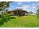 Rear view of a home with screened lanai and lush green backyard at 1415 Millbrook Cir, Bradenton, FL 34212