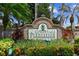 Community entrance featuring a brick sign for 'Greenfield Plantation' surrounded by lush tropical landscaping at 1415 Millbrook Cir, Bradenton, FL 34212