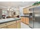 Bright kitchen featuring stainless steel appliances, light wood cabinetry, and view to the living area at 1415 Millbrook Cir, Bradenton, FL 34212