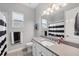 Well lit bathroom featuring a single sink vanity, a shower with black and white shower curtain, and a window at 16038 39Th E Gln, Parrish, FL 34219