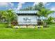A picturesque community sign surrounded by palm trees, colorful foliage, and meticulously landscaped grounds at 16038 39Th E Gln, Parrish, FL 34219