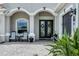 Covered front porch features double doors, chairs, a side table and exterior decor accents at 16038 39Th E Gln, Parrish, FL 34219