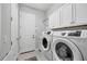 Functional laundry room with white cabinets, a washer, and a dryer at 16038 39Th E Gln, Parrish, FL 34219
