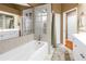 Bathroom with a bathtub, shower, and dual vanities, all accented by a large mirror and beige tile at 200 Cocoanut Ave # 1, Sarasota, FL 34236