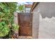 Wooden gate leading to a private entrance, surrounded by lush greenery, complemented by white garden walls at 200 Cocoanut Ave # 1, Sarasota, FL 34236