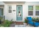 Charming entryway with a blue door, quaint porch chair, and manicured garden at 2400 Ezzell Ct, Sarasota, FL 34237