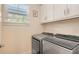 Laundry room featuring side-by-side washer and dryer, cabinets, and a window at 2410 Prospect St, Sarasota, FL 34239