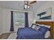 Bright bedroom features a wood headboard, a ceiling fan, a large window, and stylish decor at 2450 Dovesong Trace Dr, Ruskin, FL 33570